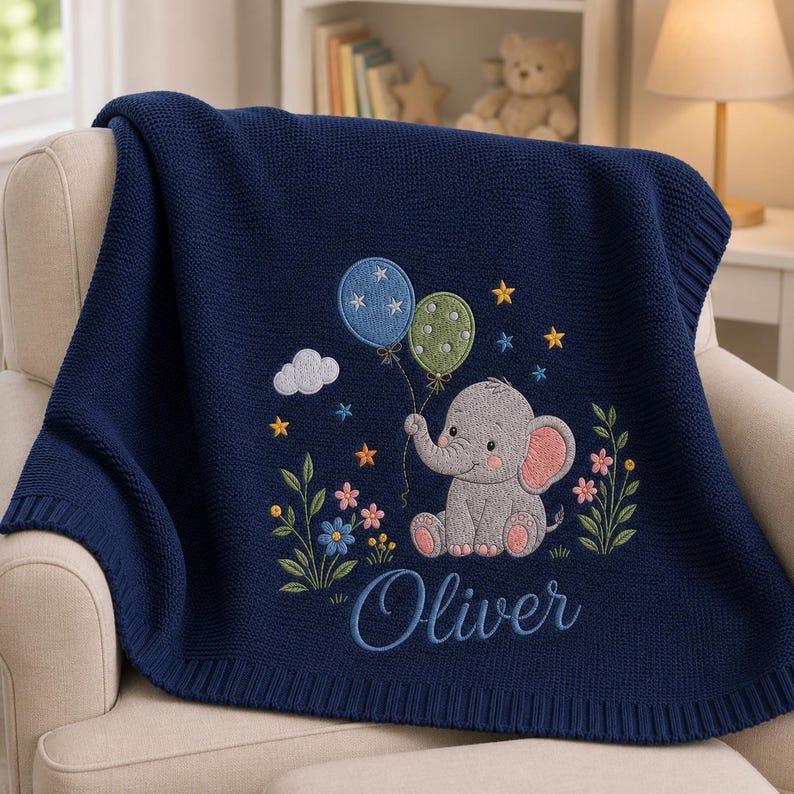 May include: A navy blue knit blanket featuring an embroidered gray elephant holding two balloons, one blue with stars and one green with dots. The design includes small yellow stars, a white cloud, colorful flowers, and the name Oliver in script.